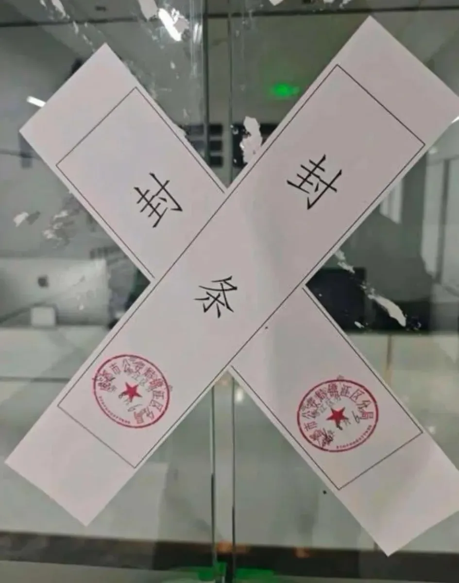 Close-up of crossed paper seal strips with red official stamps on a glass door